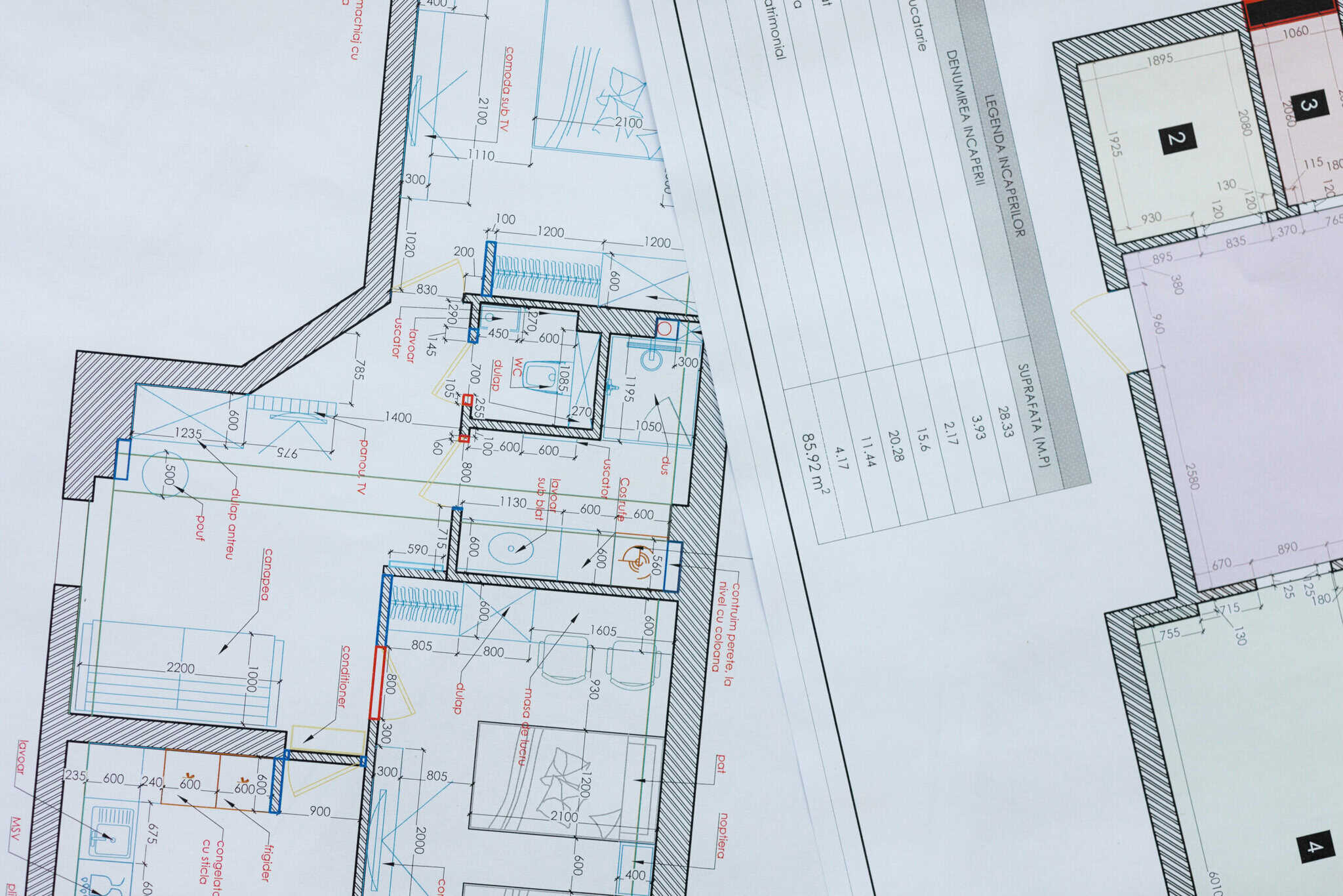 A professional woman collaborates on architectural plans showcasing various apartment and house layouts. She focuses on design details in a vibrant office setting.