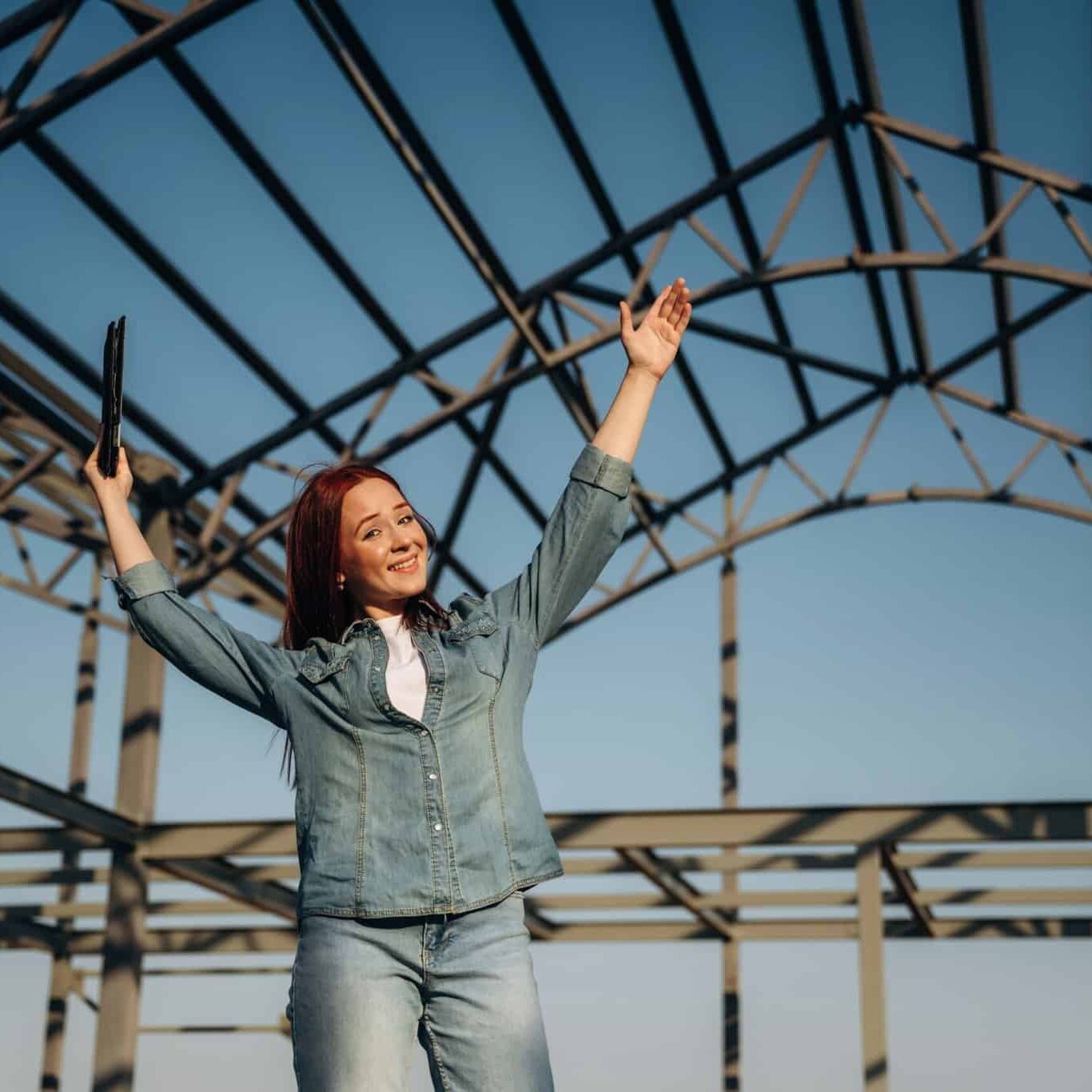 Young redhead woman is standing near unfinished building, construction Young redhead woman is standing near unfinished building, construction.